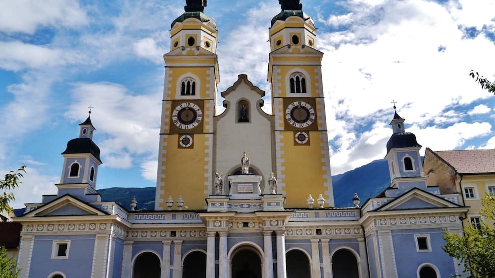 Une église dotée de deux tours, d’une grande horloge et de statues à l’entrée.
