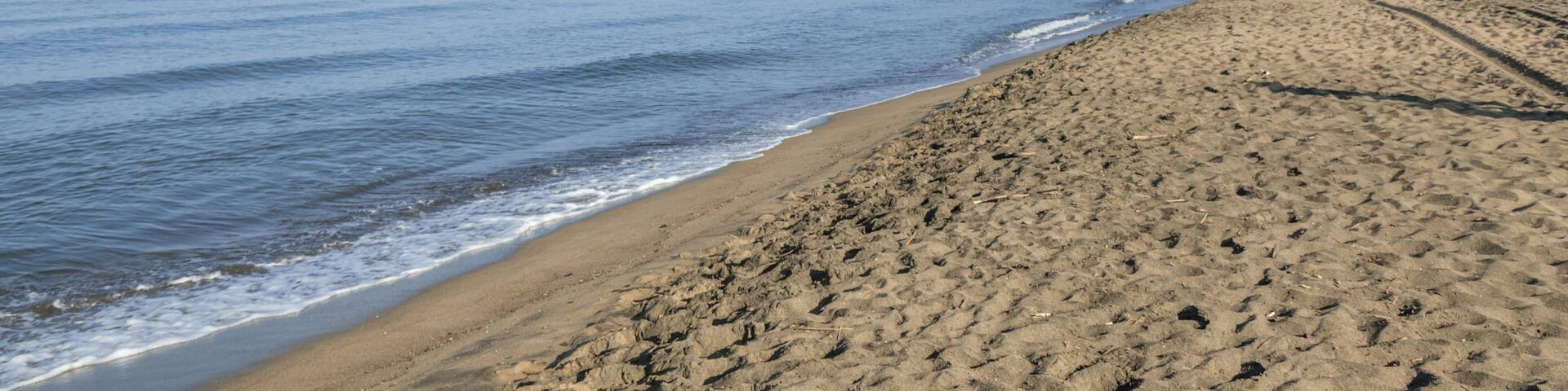 Waves and black sand of volcanic origin. Seascape of Baia Domizia, Province of Caserta, Italy