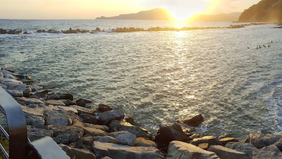 A rocky shoreline with waves crashing onto the beach during sunset.