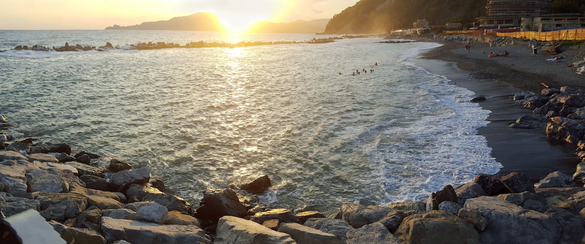 A rocky shoreline with waves crashing onto the beach during sunset.