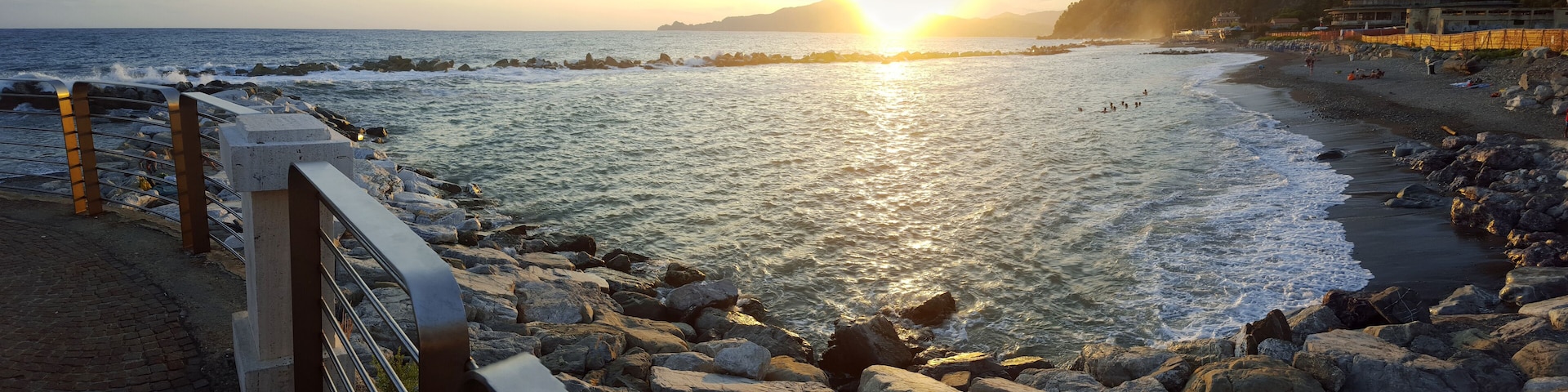 A rocky shoreline with waves crashing onto the beach during sunset.