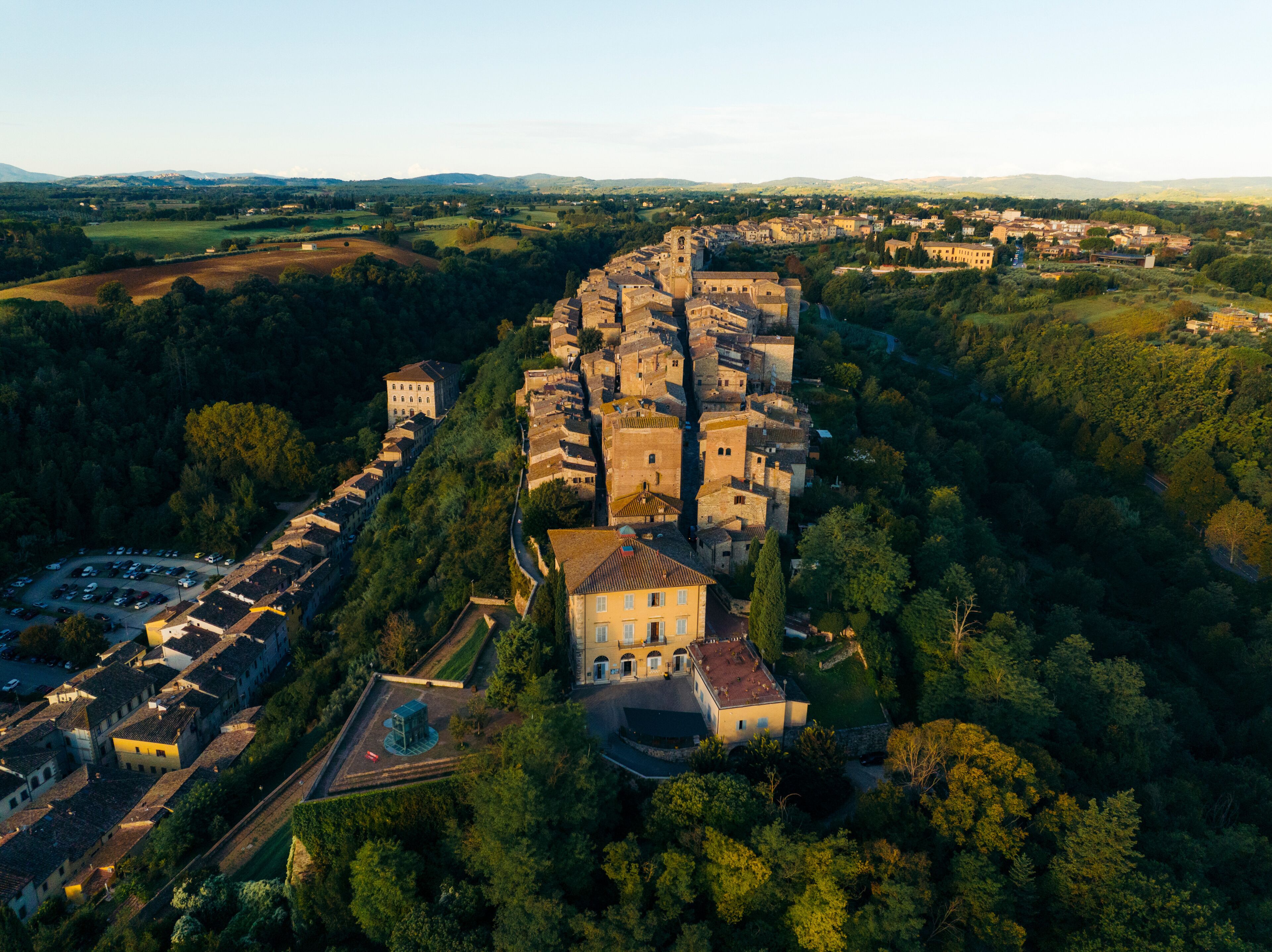 Aerial view of beautiful medieval old town with historic buildings and lush greenery, Colle di Val d'Elsa, Italy.