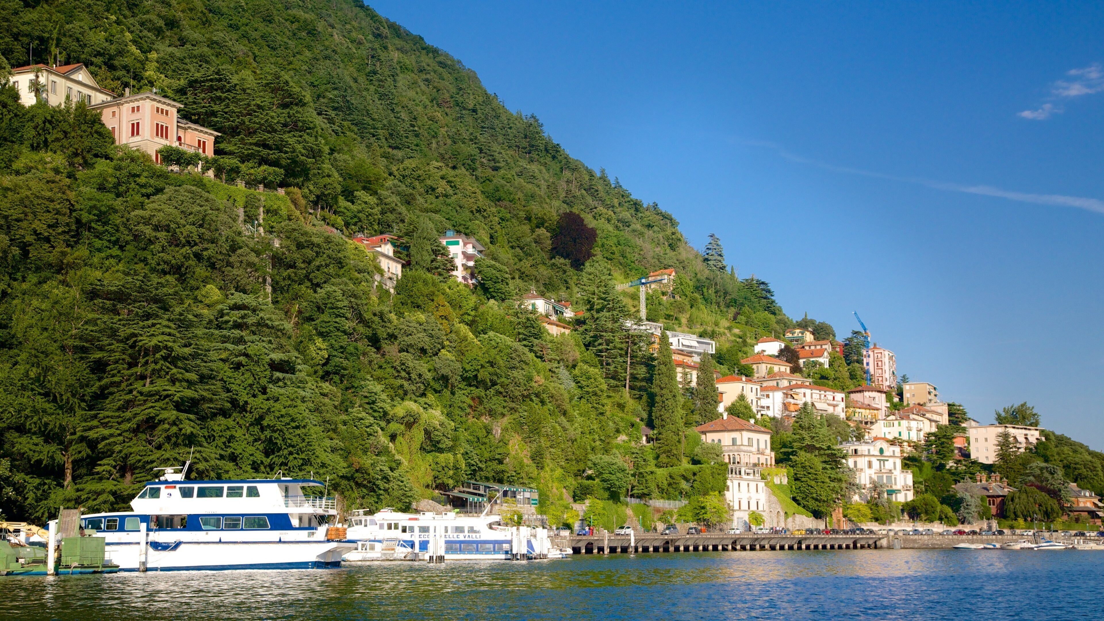 A coastal town with buildings on a hillside, a pier, and boats.