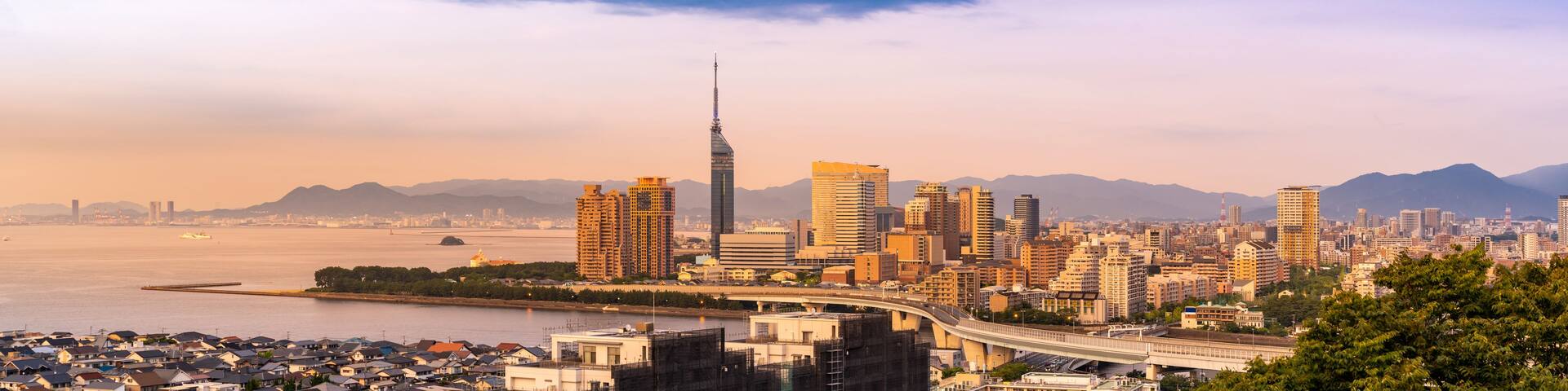 A cityscape with a prominent skyscraper, a bridge, and a body of water.
