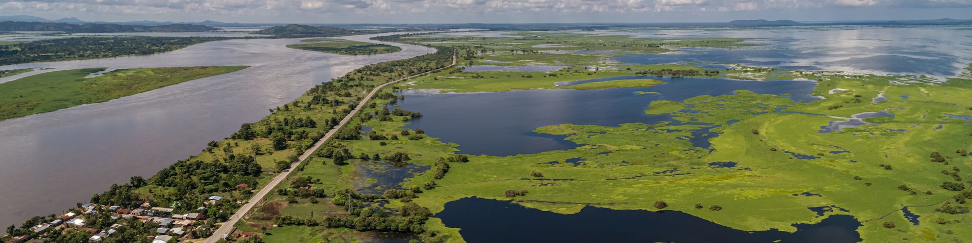 Um rio serpenteando por uma paisagem verde com uma pequena cidade às suas margens.