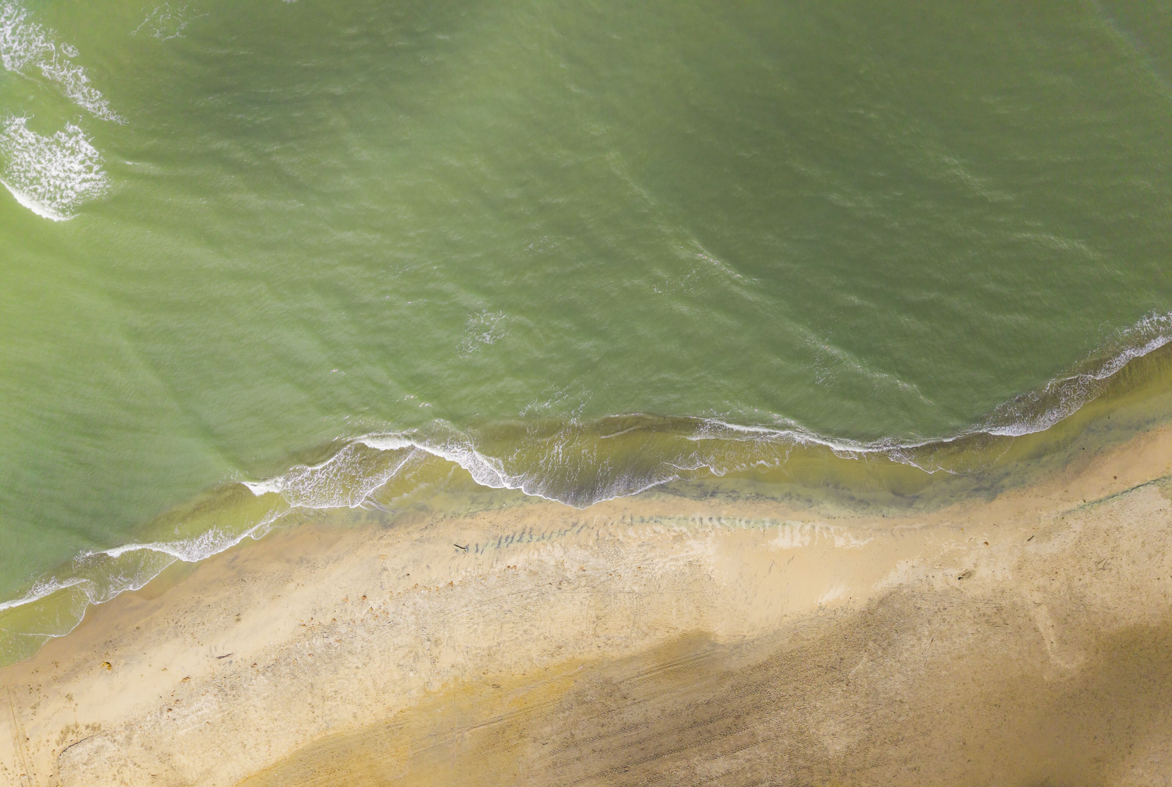 A sandy beach with gentle waves lapping at the shore.