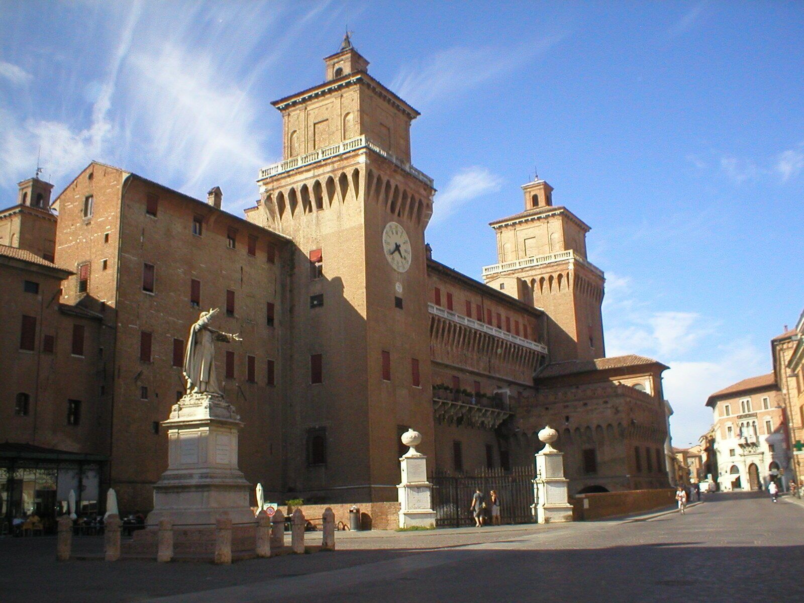A historic building with a clock tower and a statue in the foreground.