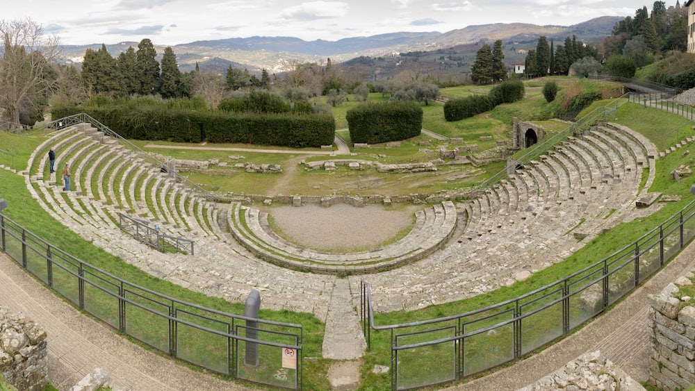 Ruins of the ancient Roman theater in Fiesole, near Florence, Italy, built in the 1st century BC, with semicircular seating and scenic backdrop.