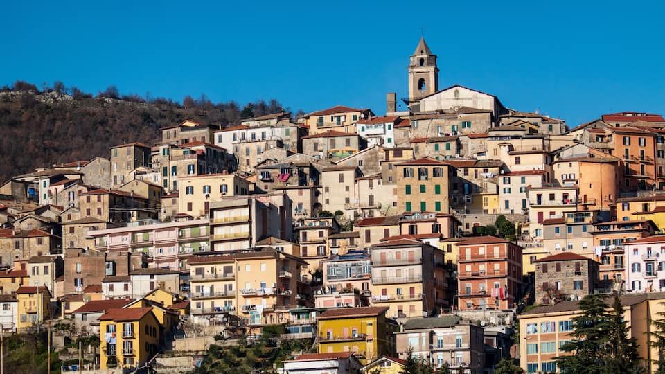A densely packed hillside town with colorful buildings and a prominent church tower.
