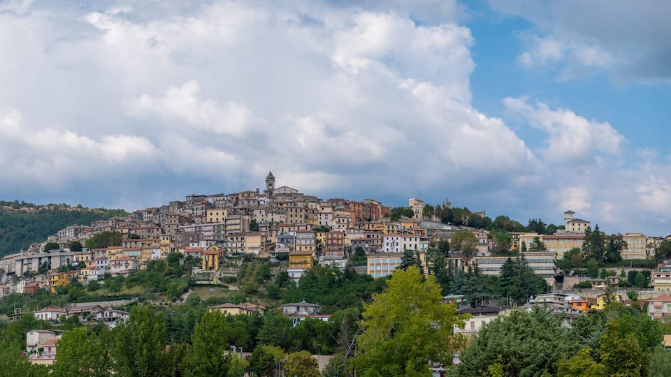 A hillside town with colorful buildings, a prominent church, and a tower on the summit.