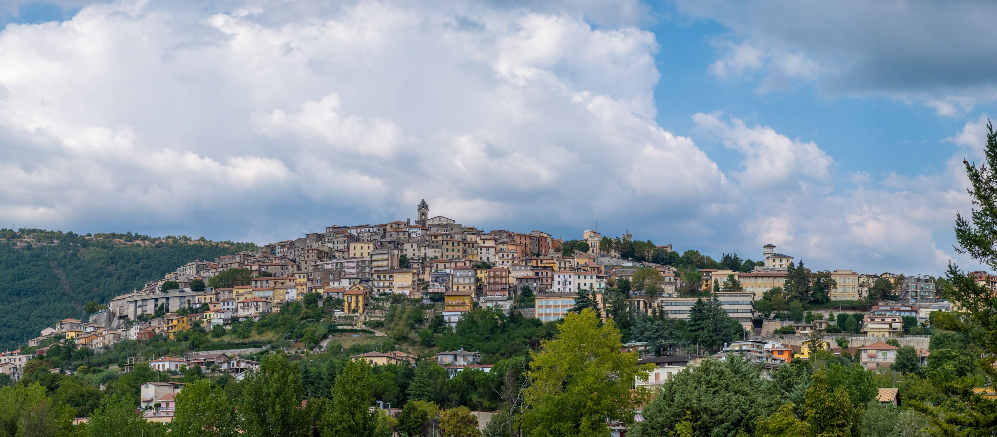 A hillside town with colorful buildings, a prominent church, and a tower on the summit.