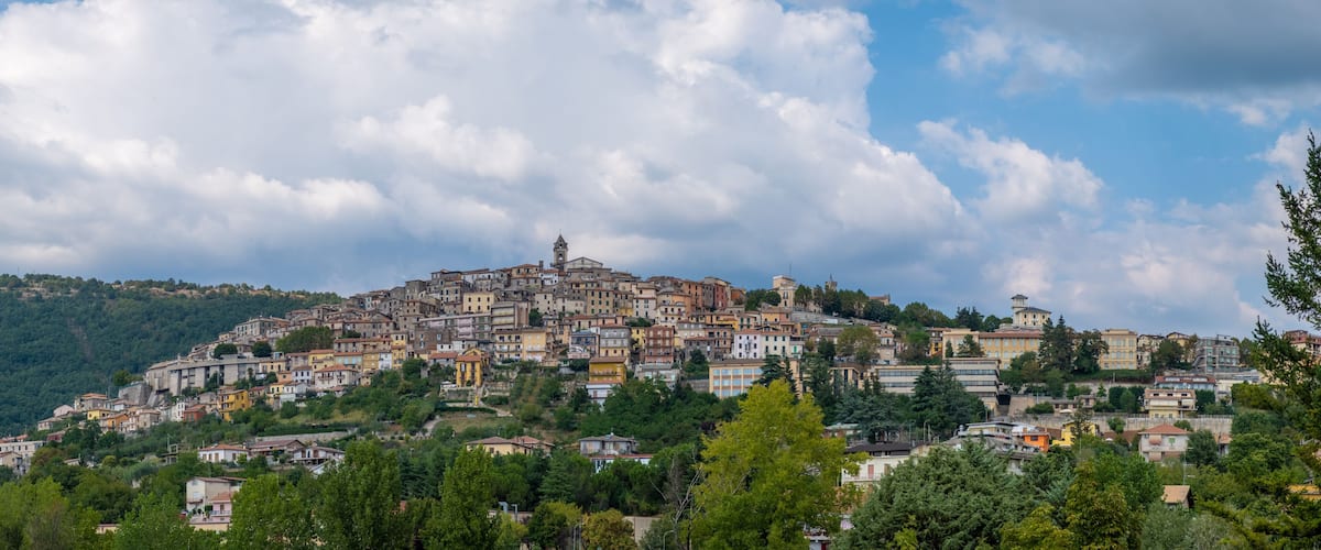 A hillside town with colorful buildings, a prominent church, and a tower on the summit.