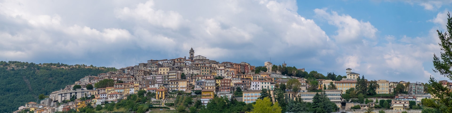 A hillside town with colorful buildings, a prominent church, and a tower on the summit.