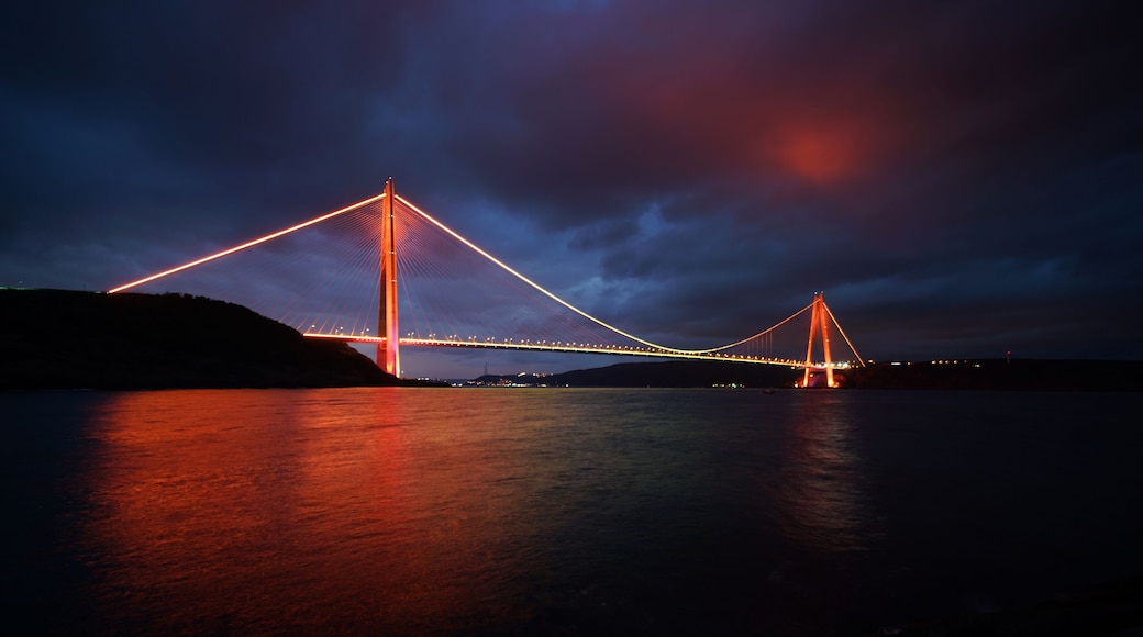 Osmangazi Bridge. The photo of the bridge taken from the front while its colorful lights are on at night. The bridge lights are reflected on the sea, creating a magnificent view.