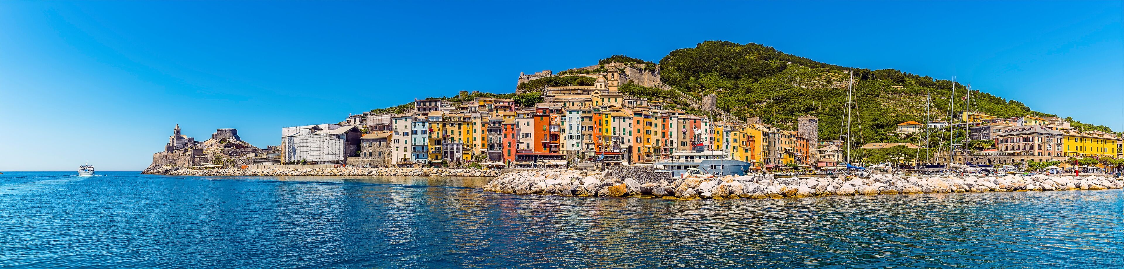 A coastal town with colorful buildings, a historic fort, and a clear blue sea.