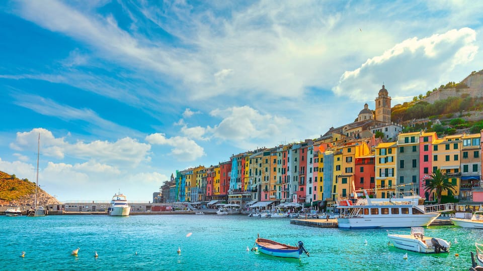 A coastal town with colorful buildings, a prominent church, and boats in the water.