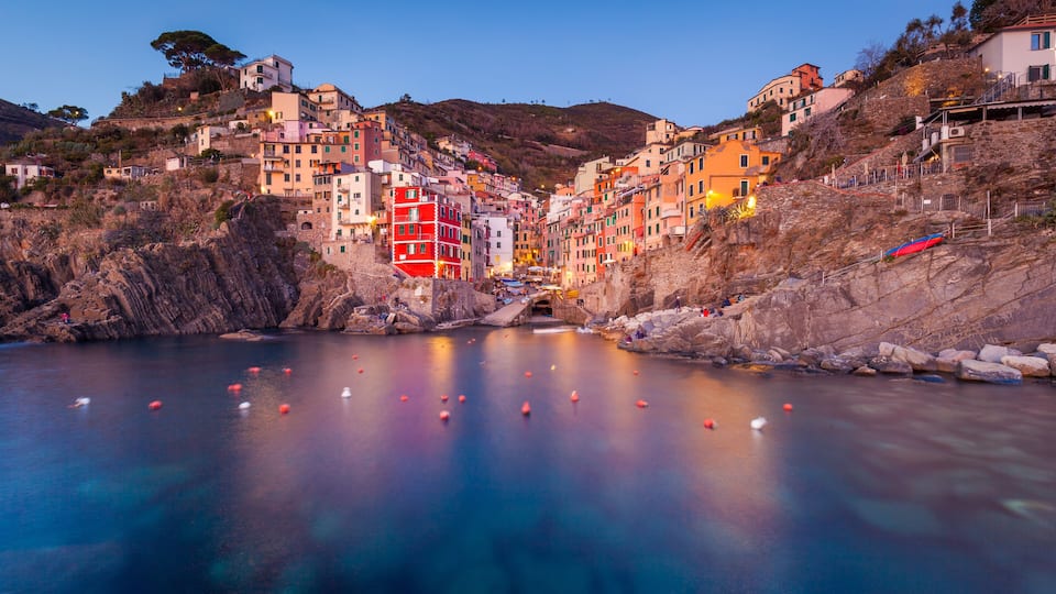 A coastal village with colorful buildings, a calm sea, and a rocky shoreline.