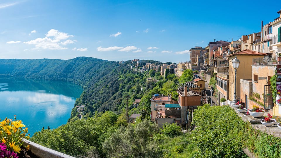 A coastal town with buildings overlooking a lake, surrounded by greenery.
