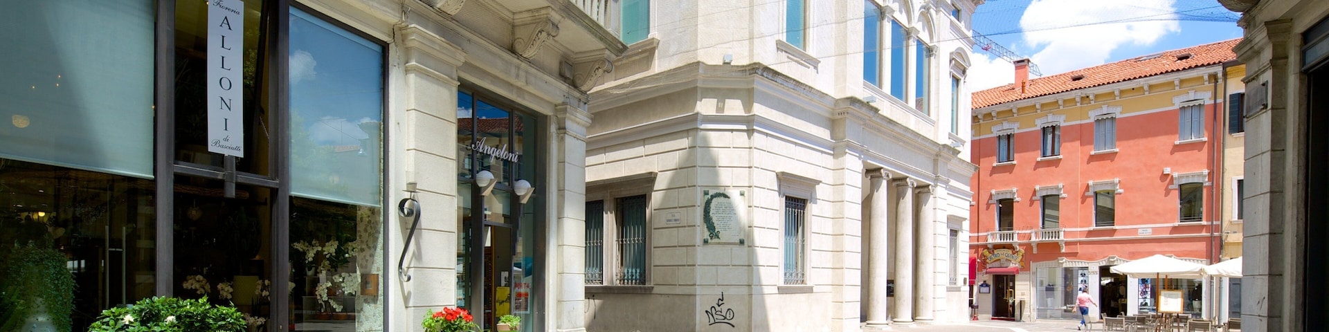 A street with a flower shop, a building with a sign reading "Teatro Tonino", and a red building in the background.