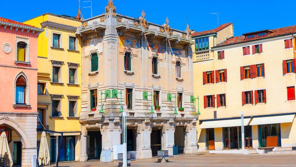 Un bâtiment historique à l’architecture riche et ornée, doté d’une façade jaune éclatante et de volets rouges.