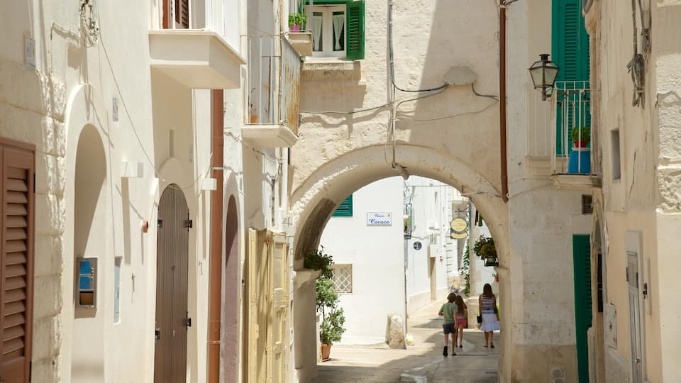 A narrow street with an archway, buildings with shutters, and a sign for 'Cacace'.
