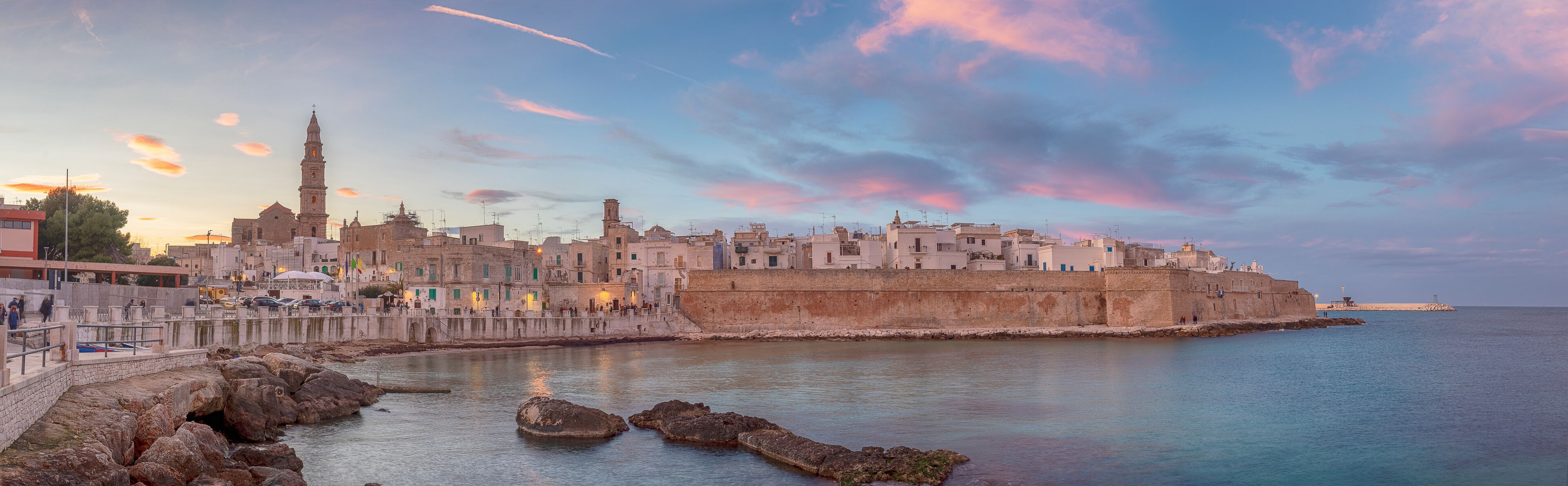 Sunset panorama of Monopoli harbor in the Metropolitan City of Bari and region of Apulia ( Puglia ) , Italy and beautiful illuminated cathedral Basilica Concattedrale Maria Santissima della Madia