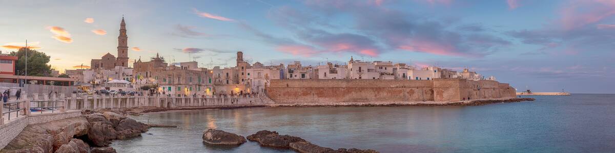 Sunset panorama of Monopoli harbor in the Metropolitan City of Bari and region of Apulia ( Puglia ) , Italy and beautiful illuminated cathedral Basilica Concattedrale Maria Santissima della Madia
