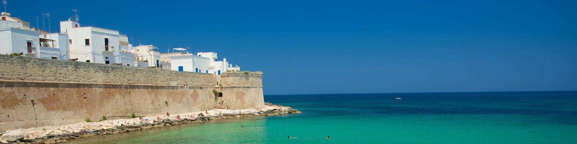 Monopoli which includes a pebble beach and rugged coastline as well as a large group of people