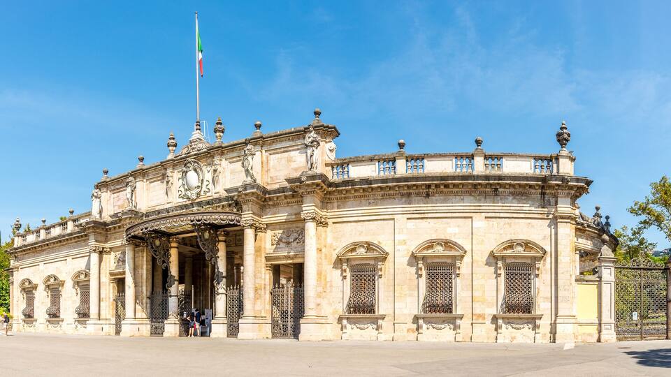 A historic building with ornate architecture, a flagpole, and a gated entrance.