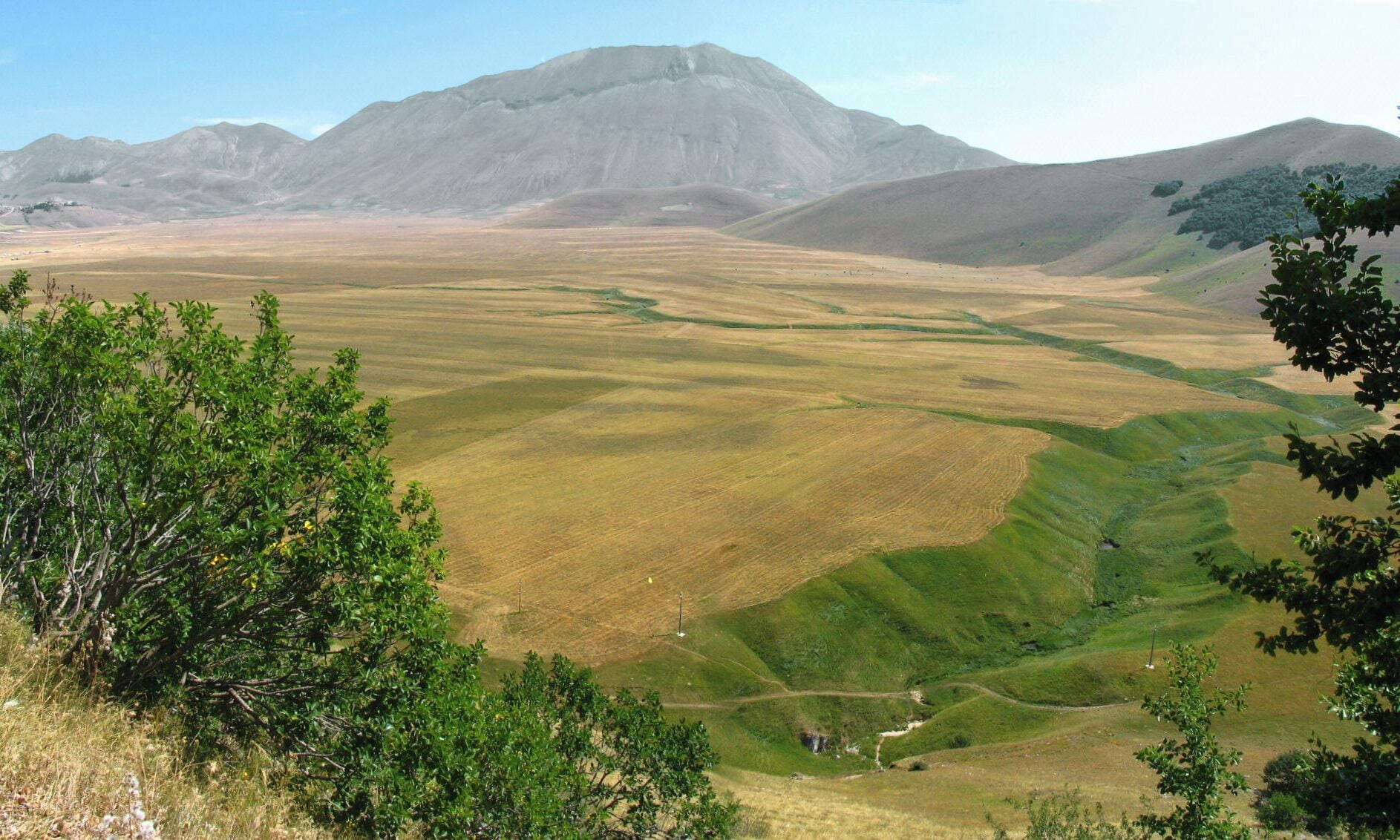 Un paisaje extenso y ondulado, con una montaña destacada al fondo.