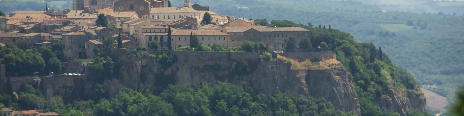Un pueblo histórico asentado sobre un acantilado, con una iglesia y un castillo destacados.