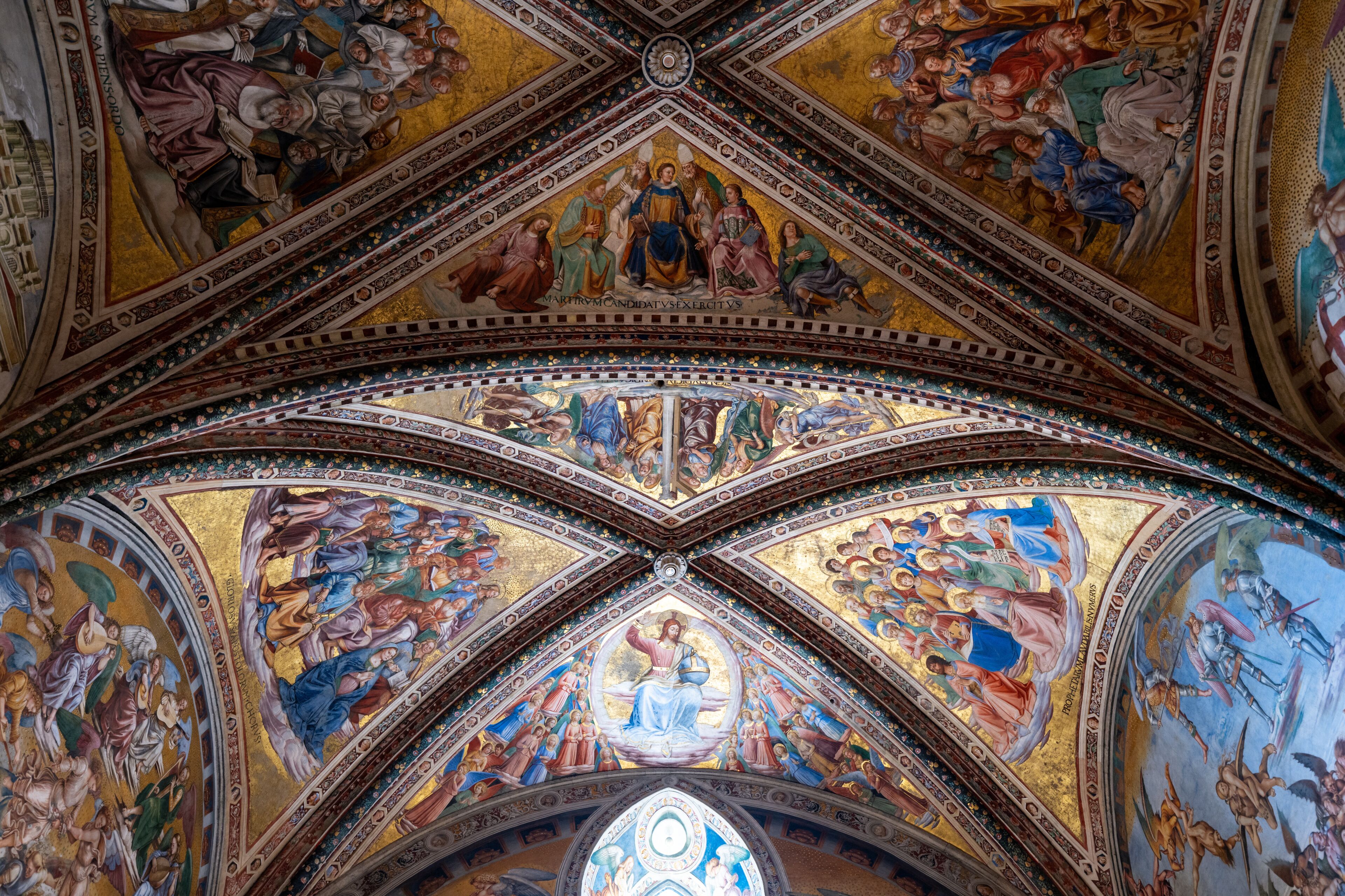 A detailed ceiling fresco with religious figures and scenes, intricate geometric patterns, and a central circular design.