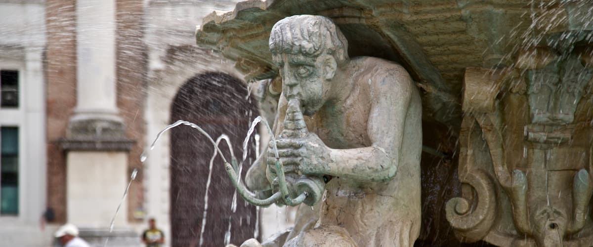 A stone fountain with a sculpture of a figure playing a flute, surrounded by water spouts.