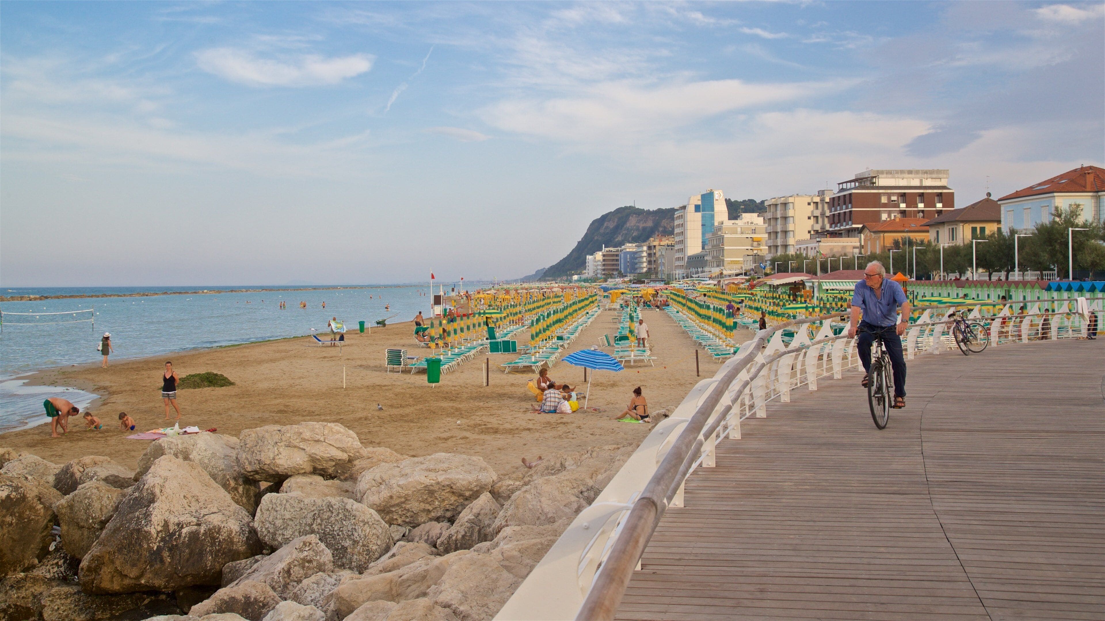 A beach with rows of sun loungers and a wooden boardwalk.