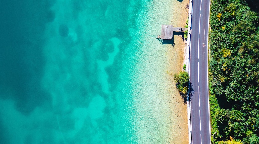 A turquoise beach with clear waters, a paved road, and wooden structures.