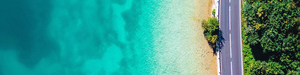 A turquoise beach with clear waters, a paved road, and wooden structures.