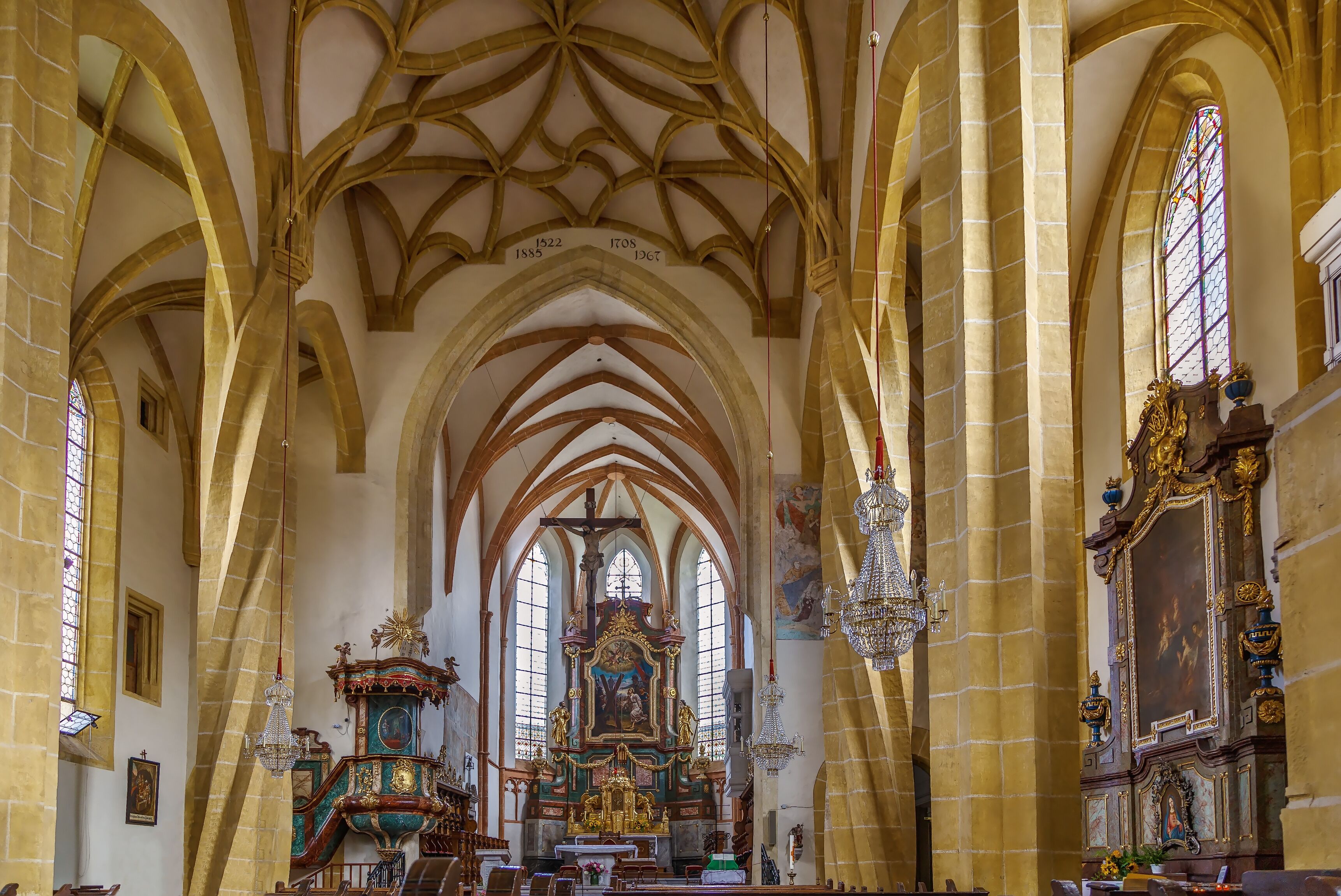 A cathedral interior with high vaulted ceilings, stained glass windows, and ornate religious artwork.