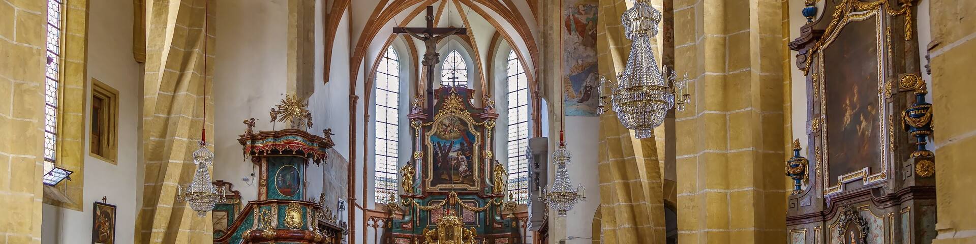 A cathedral interior with high vaulted ceilings, stained glass windows, and ornate religious artwork.