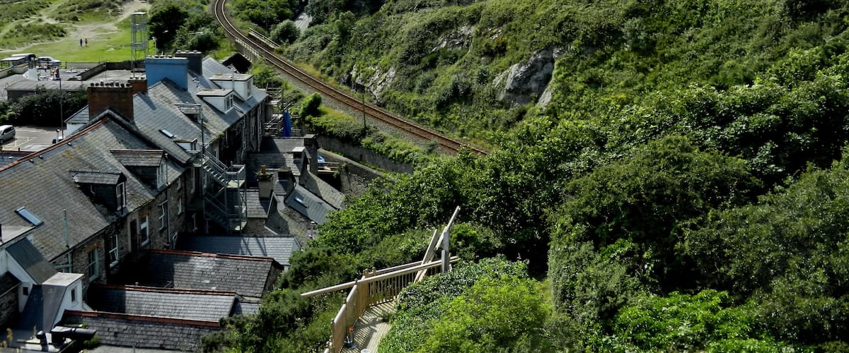 A railway track curving through a hilly area with buildings and greenery.
