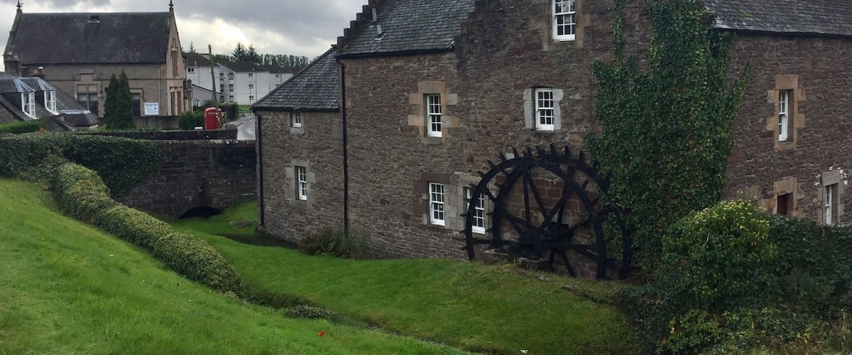 A historic stone building with a large water wheel and a cross on the roof.