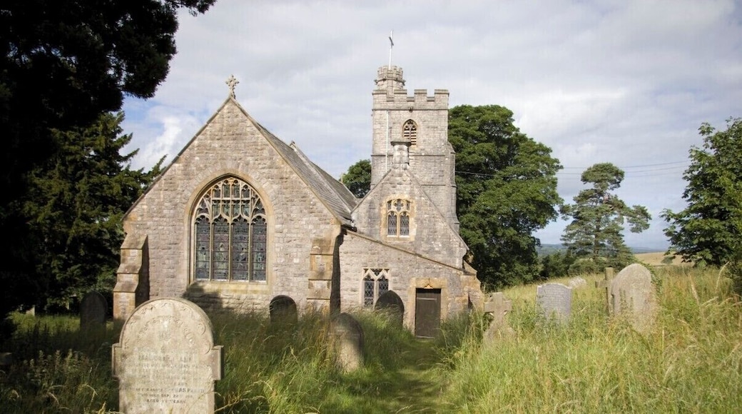 A stone church with a tall tower and arched windows, surrounded by a graveyard with headstones.