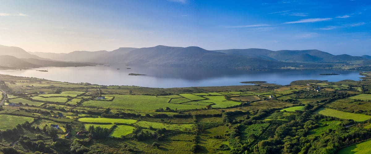 A panoramic view of a lake surrounded by rolling hills and fields.