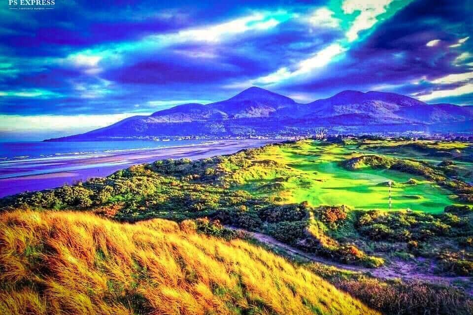 A coastal landscape with mountains, a golf course, and a beach.