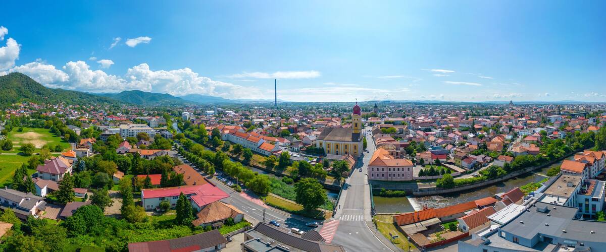 A panoramic view of a city with a prominent church, a river, and surrounding greenery.