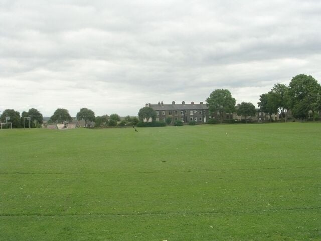 A large green field with a building in the background.
