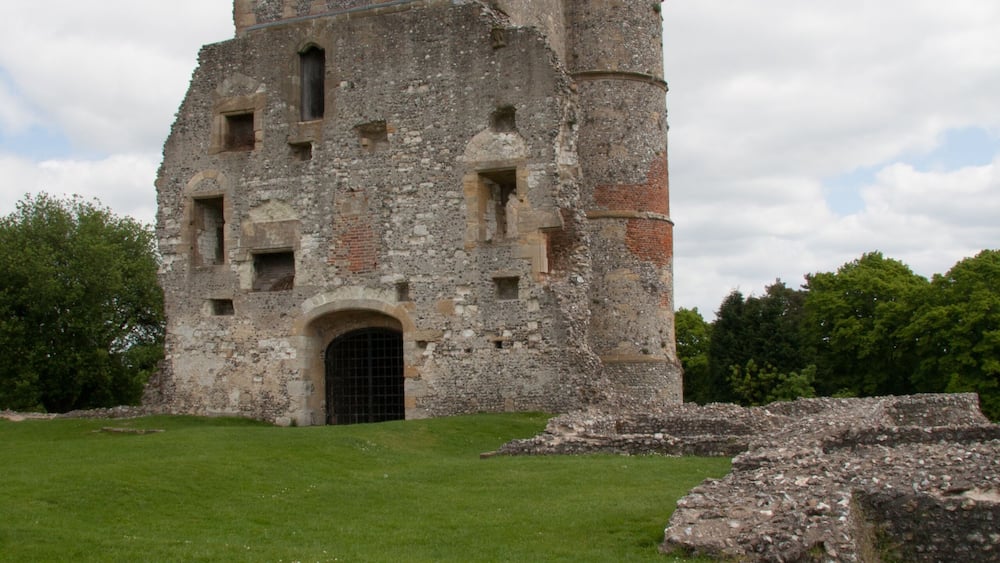 Un ancien château de pierre, avec une cour verdoyante et des ruines au premier plan.