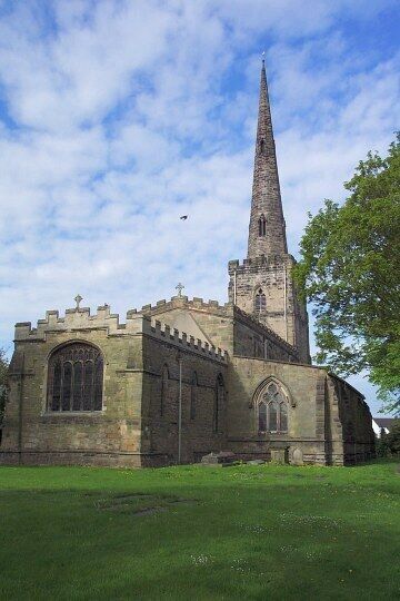 A historic church with a tall spire and a large arched window.