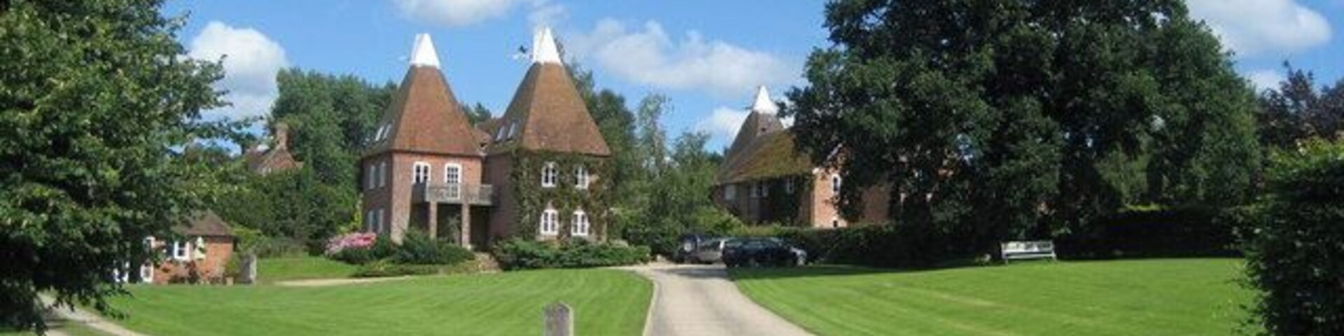 A rural road leading to a large house with a thatched roof.