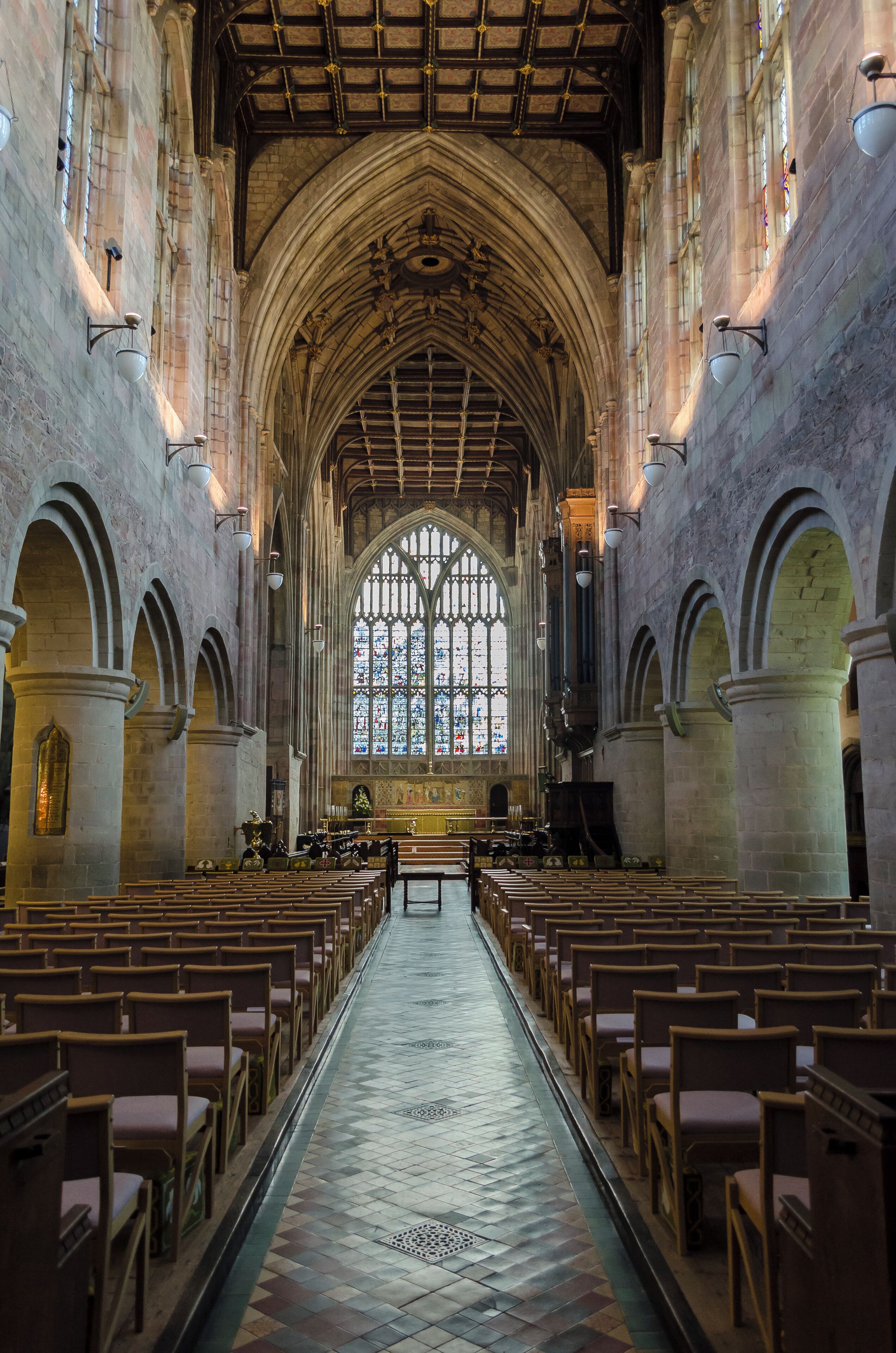 A cathedral interior with arched ceilings, stained glass windows, and rows of pews.