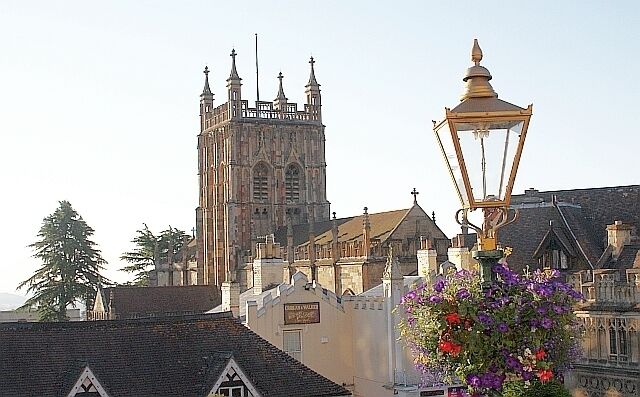 Un edifici històric amb una torre alta, un llum de carrer i una cistella de flors.